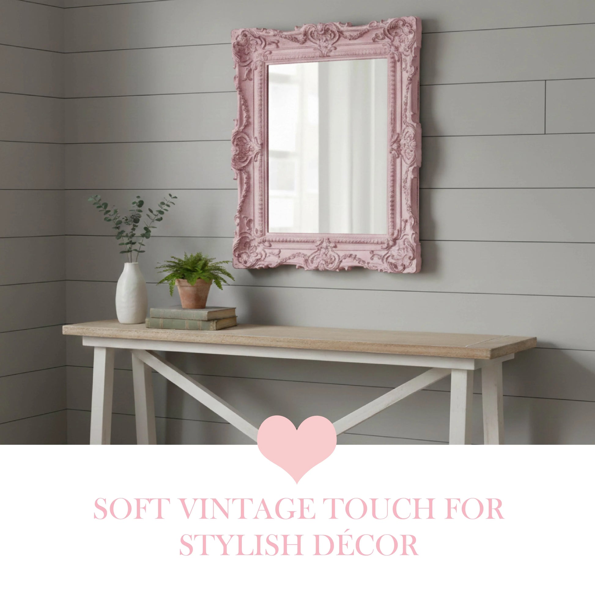 Pink ornate mirror above a wooden table with decorative items on a gray paneled wall.