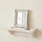Pretty Shabby Wall Mirror – Rectangular Chic with ornate white frame displayed on a matching shelf against a beige wall