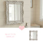 Decorative silver mirror with intricate details in a bathroom setting.