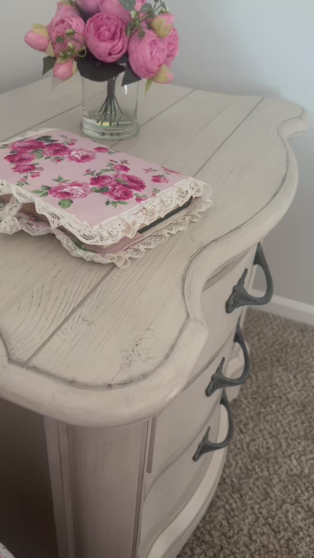 Fleur Quran cover with lace trim on wooden side table with glass vase and flowers in it.