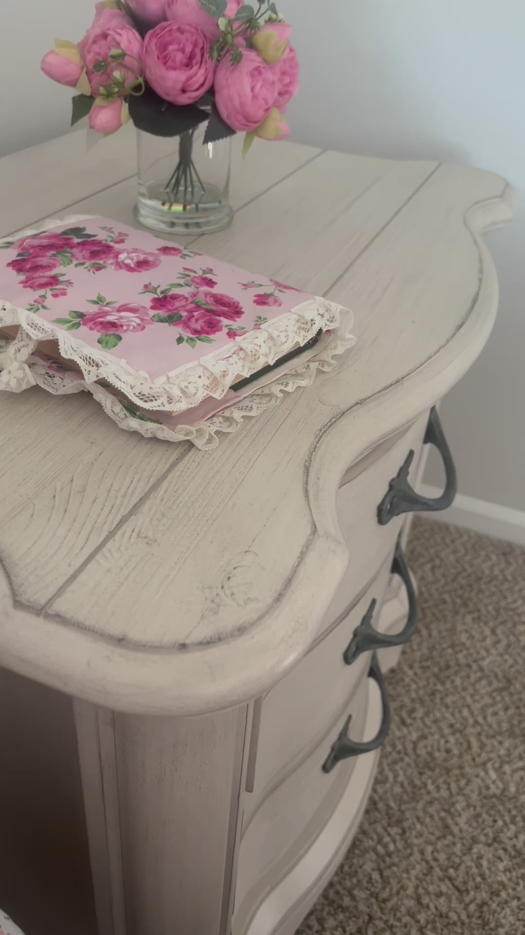 Fleur Quran cover with lace trim on wooden side table with glass vase and flowers in it.