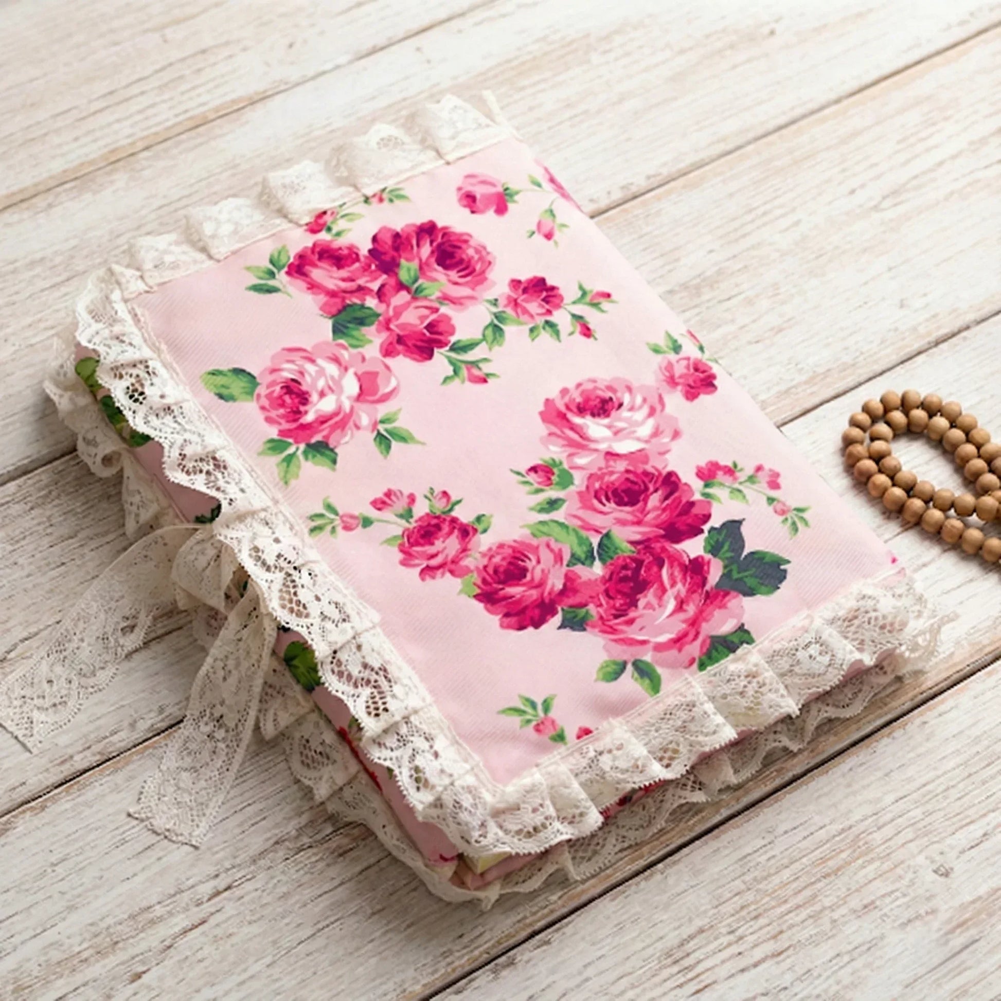 Floral fabric with pink roses on a wooden surface