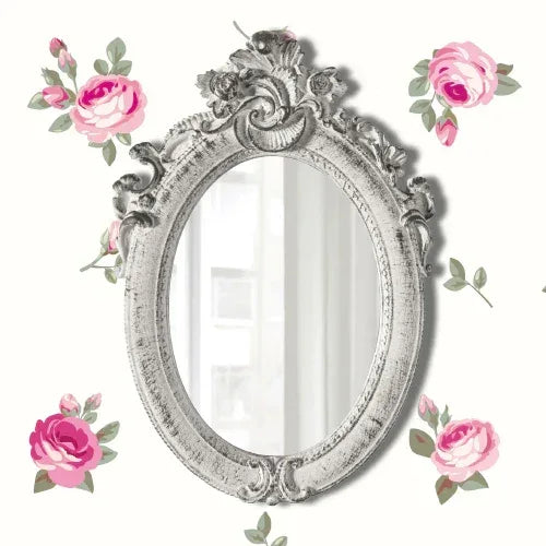 Ornate vintage oval mirror with floral frame against white background with pink rose patterns