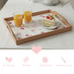 Wooden tray with floral print holding juice and cake, above pink icons for eco-friendly, durable, and solid wood.