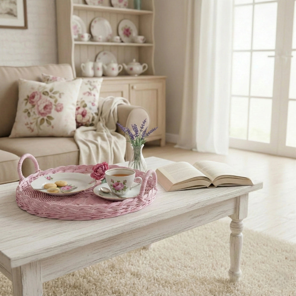 Living room with a coffee table featuring a Round Pink wicker tray, a tea set, a book, and decorative items in it 