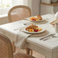 Round Wicker Placemat on a breakfast table with woven chairs, white dinnerware, croissants, fruit, and beige tablecloth