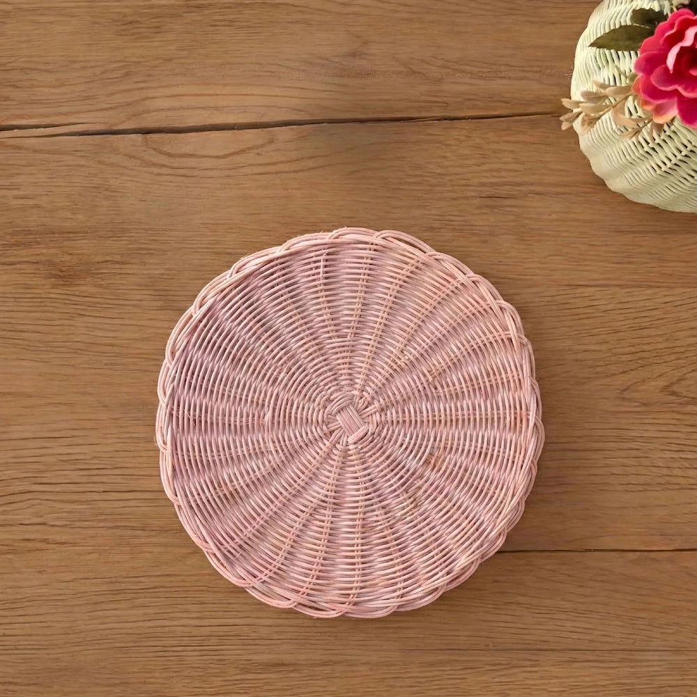 Round Wicker Placemat in pink woven design displayed on a wooden dining table