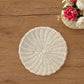Round Wicker Placemat with scalloped woven design displayed on a wooden table beside a floral arrangement
