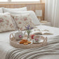 Round Wicker Tray styled as breakfast setup with teapot, cookies, coffee, floral pillows on bed