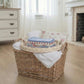 Round Wicker tray on a Wicker laundry basket with folded clothes in it and a wooden floor.