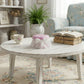 Round wooden coffee table with decorative items in a cozy living room.