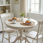 Round wooden dining table with chairs in a bright room