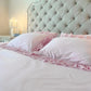 Ruffled Bedding Set in pale pink with tufted headboard and matching pillowcases in a bedroom setting