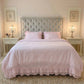Ruffled Bedding Set in pale pink styled on a bed with tufted headboard in a bedroom
