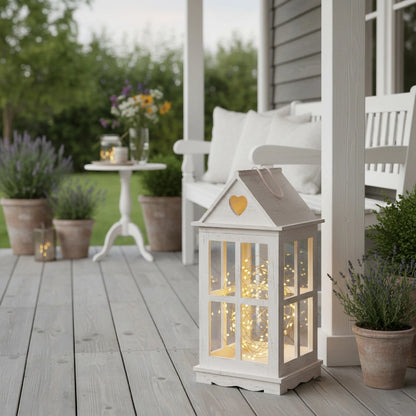 Rustic Wooden Heart Cut-Out Lantern with fairy lights on wooden deck beside plants and chair