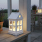 Decorative outdoor lantern with heart-shaped window on a wooden surface, evening setting.