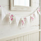 Shabby Chic Fleur & Polka Dot Pennant Banner Flag with a mix of pink rose floral and light polka dot triangles, hanging across a white shiplap wall beneath a rustic wooden mirror.