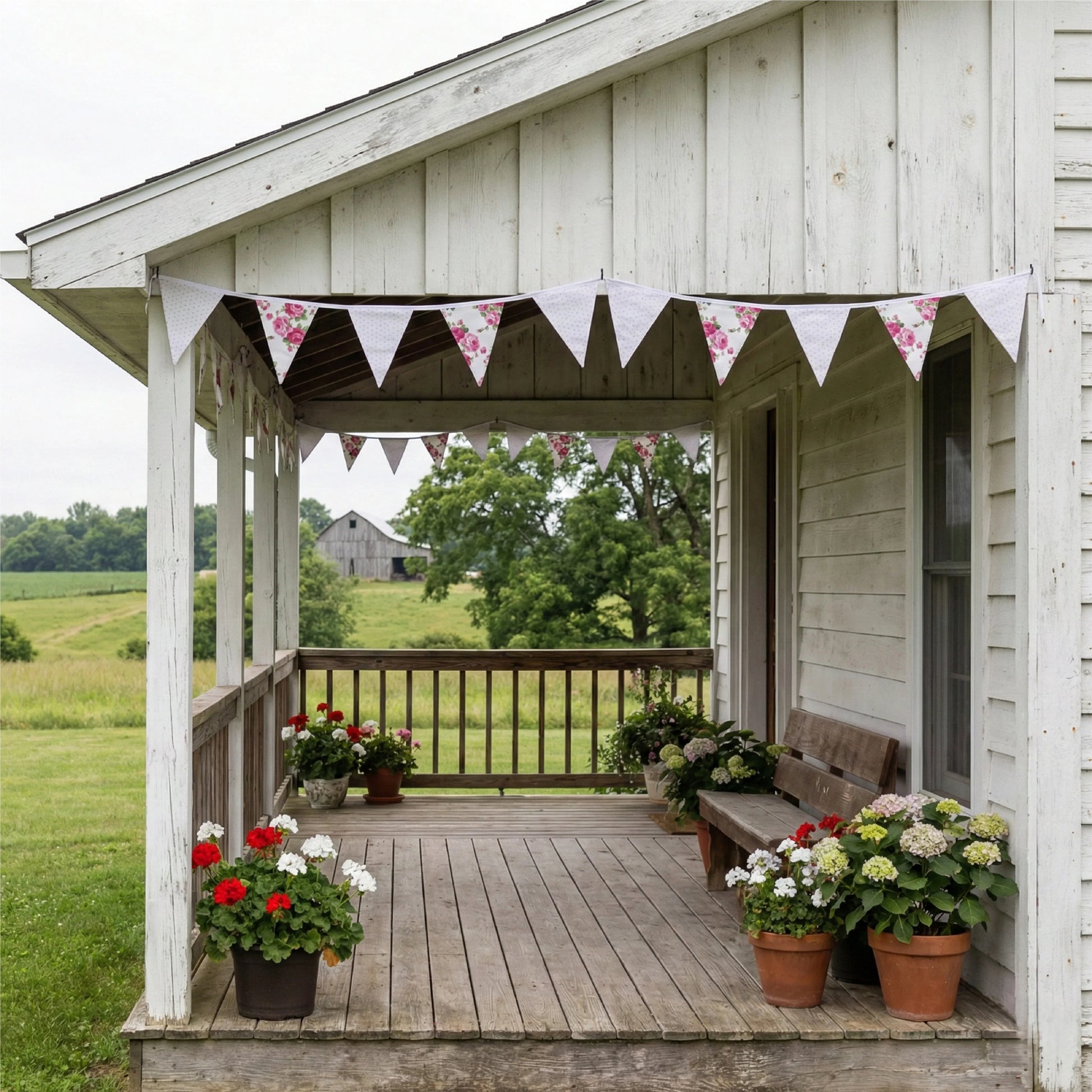 Wooden porch with potted flowers and a scenic view of a barn and fields.