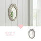 Ornate white ribbon mirror mounted on a white wood paneled wall with a pink heart icon and "Beauty in Display" text.