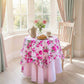 Table with floral tablecloth in a bright room with large windows.