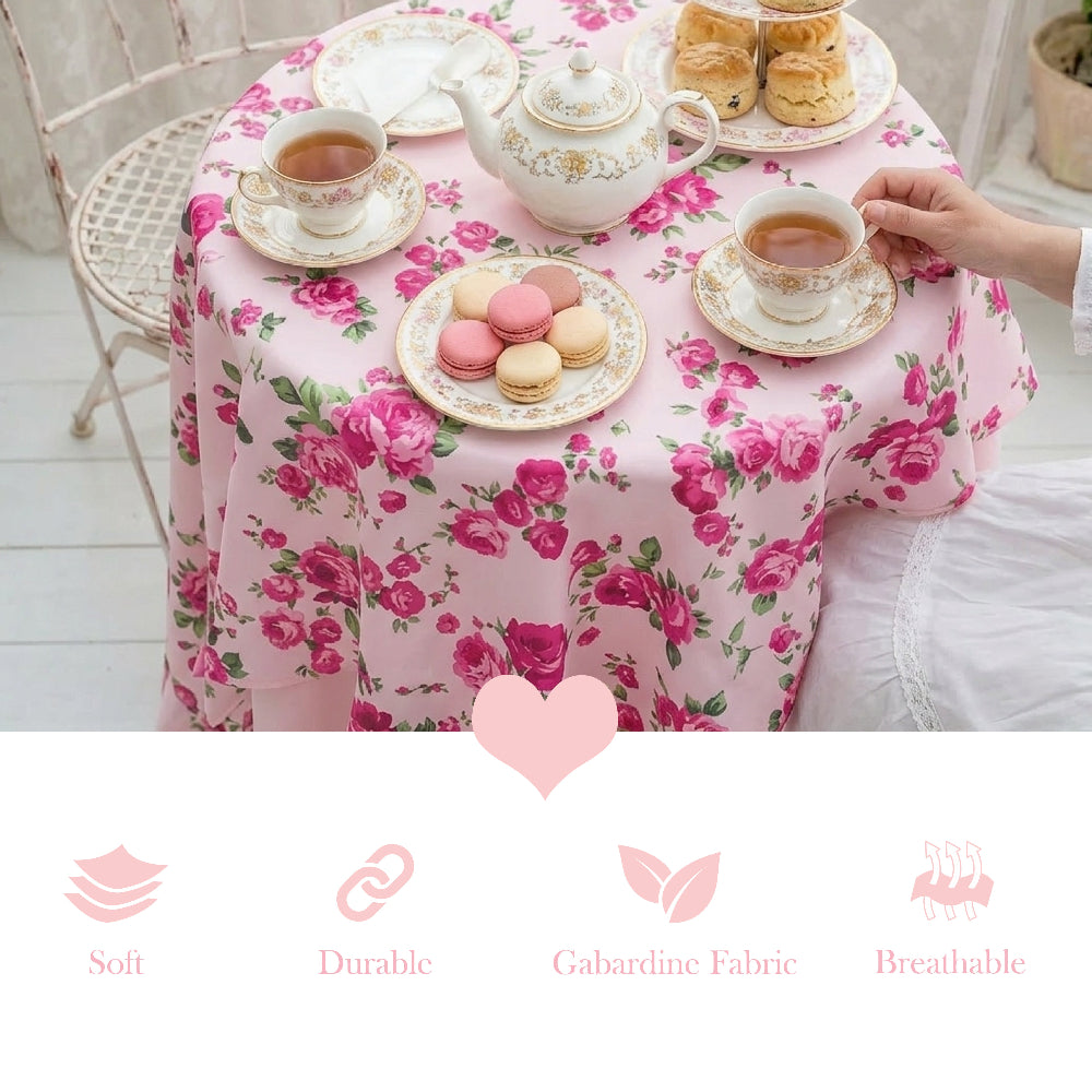 Tea set on a floral tablecloth with tea cups, teapot, and pastries.