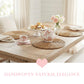 Tea set on a wooden table with woven placemats and a pink heart graphic.