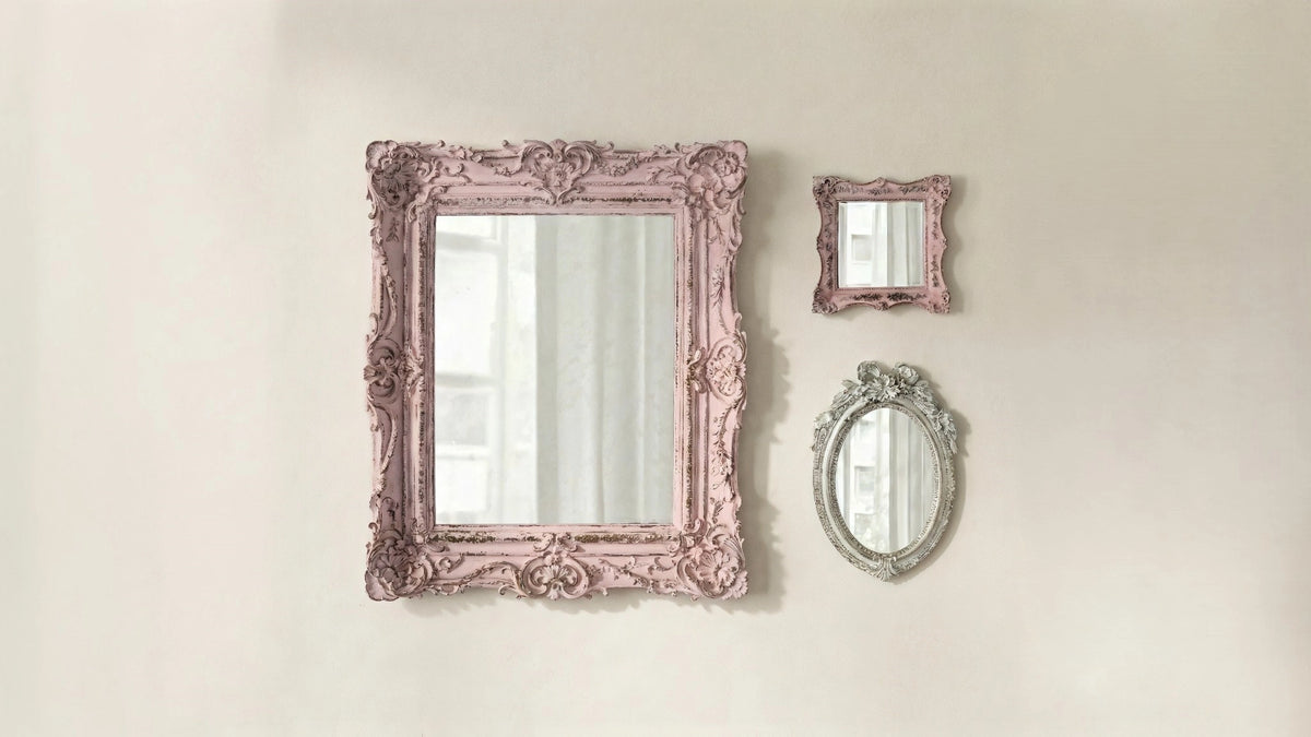 Three decorative mirrors with ornate pink frames on a beige wall.