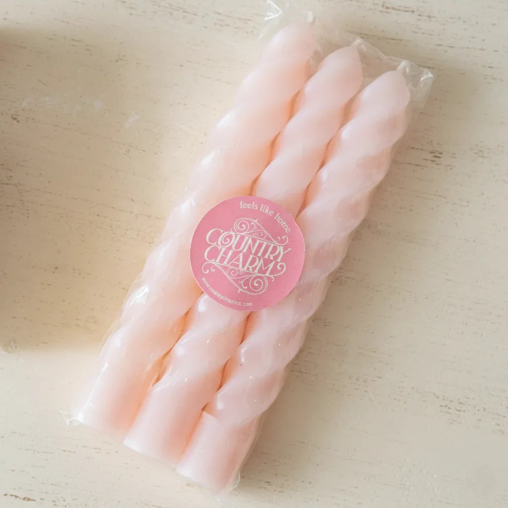 Packaged pink candles with a 'Country Charm' label on a light wooden surface