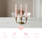 Pink candles in a brass candlestick holder on a wooden table with a neutral background