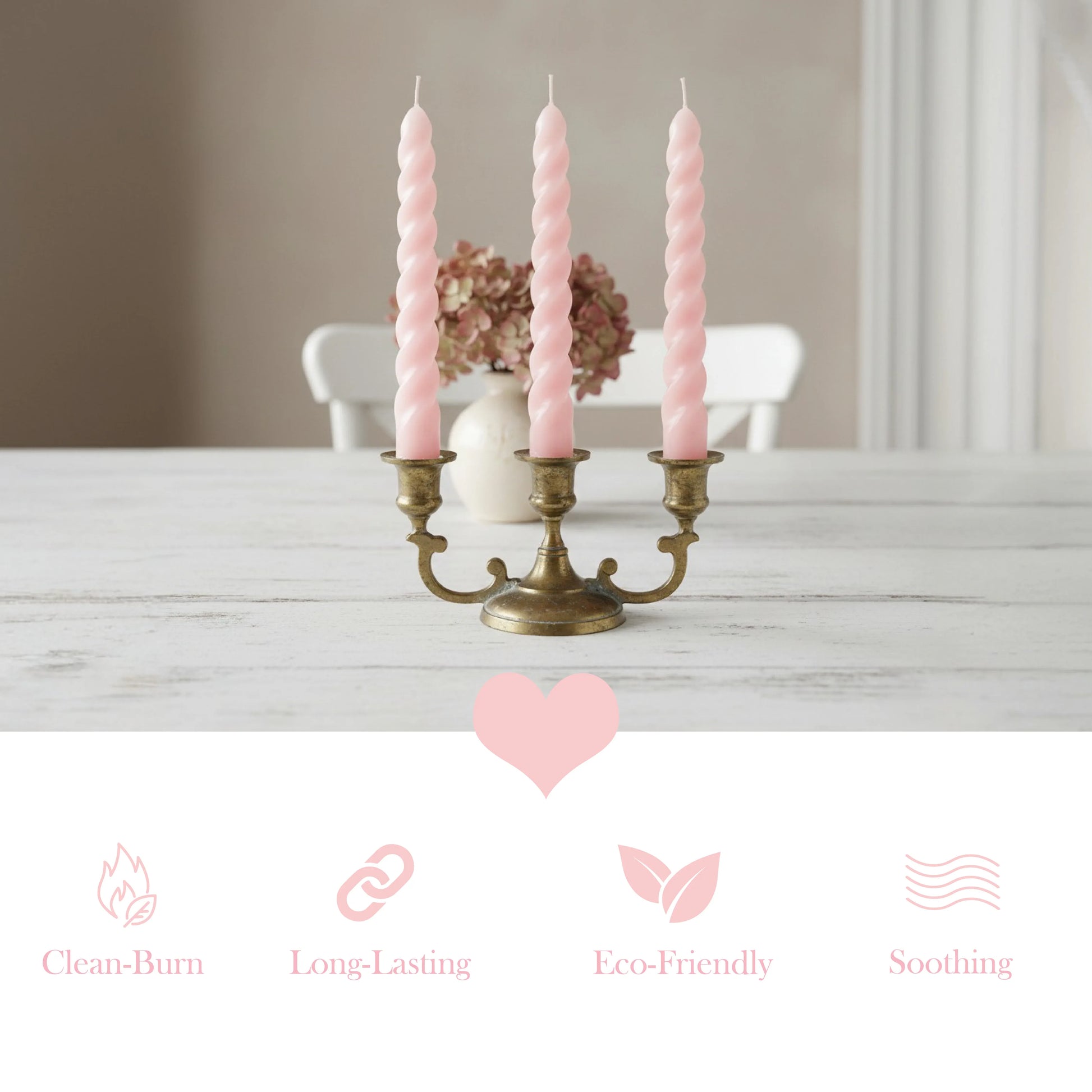 Pink candles in a brass candlestick holder on a wooden table with a neutral background