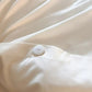 Close-up of a white button closure on off-white fabric with soft, draped folds