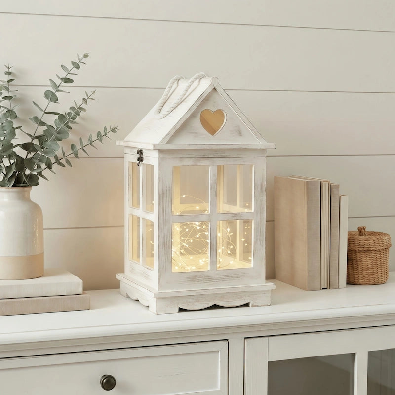 White decorative heart cutout lantern with heart design on a shelf with books and a plant.