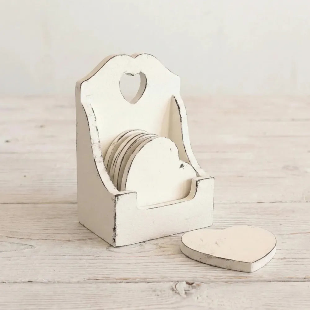 White heart-shaped coasters in distressed wooden holder with heart cutout displayed on light wood surface for home decor