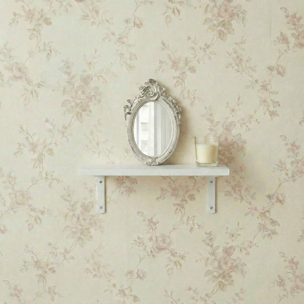 Ornate white oval mirror and a candle on a white shelf against floral rose wallpaper.