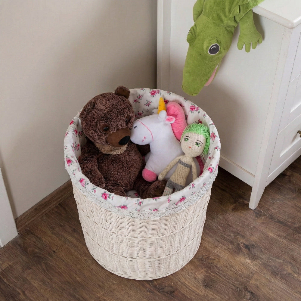 White wicker basket with floral lining filled with a teddy bear and stuffed toys on a wooden floor.