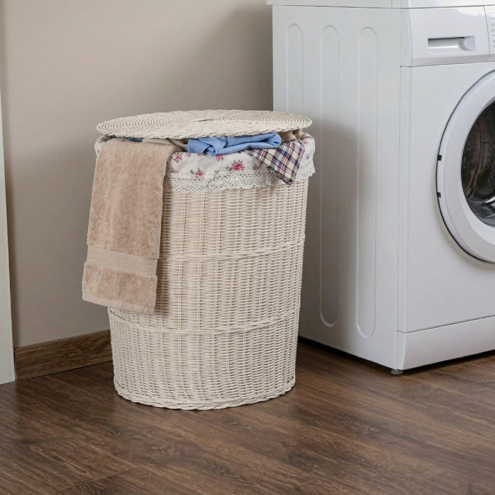 White wicker laundry hamper with floral lining and lid next to a washing machine on a wooden floor.
