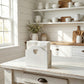 White wooden box with a heart cutout on a rustic wooden table in a kitchen.