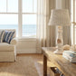 Wicker Shade Side Lamp beside living room couch table with large window and ocean view
