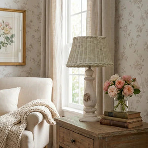 Wicker Shade Side Lamp on a wooden side table with books and flowers in a living room