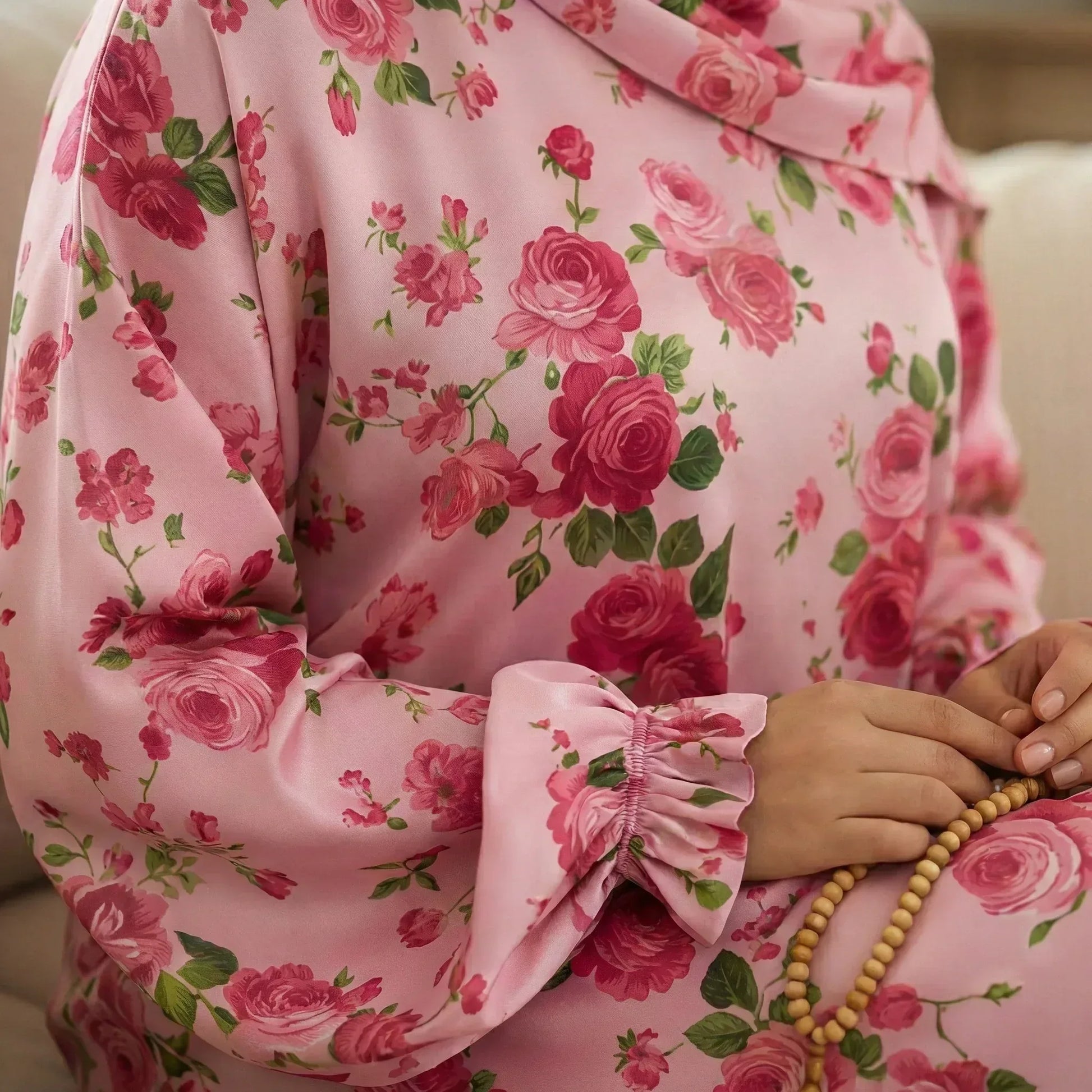 Person wearing a pink floral dress holding a rosary.