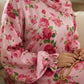 Person wearing a pink floral Isdal Prayer dress holding a rosary.