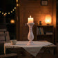 Wooden candle holder with a lit candle against a dark night background.